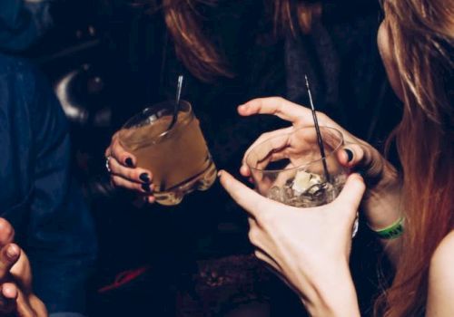 People are socializing and holding drinks in a lively, indoor setting.